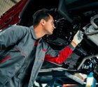 Automotive technician inspecting underneath a raised vehicle