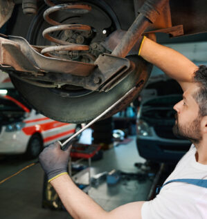 Mechanic inspecting a vehicle coil spring and suspension system in Edmonton