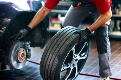Closeup of a 40's male care mechanic replacing a tire at a car repair shop