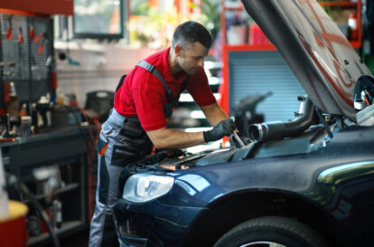 Closeup of a 40's male care mechanic working on an engine at a car repair shop