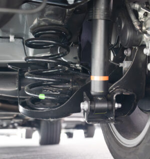 Close-up of a vehicle shock absorber and coil spring during a suspension inspection