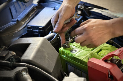 Adult hand using spanner to install new car battery for motor vehicle
